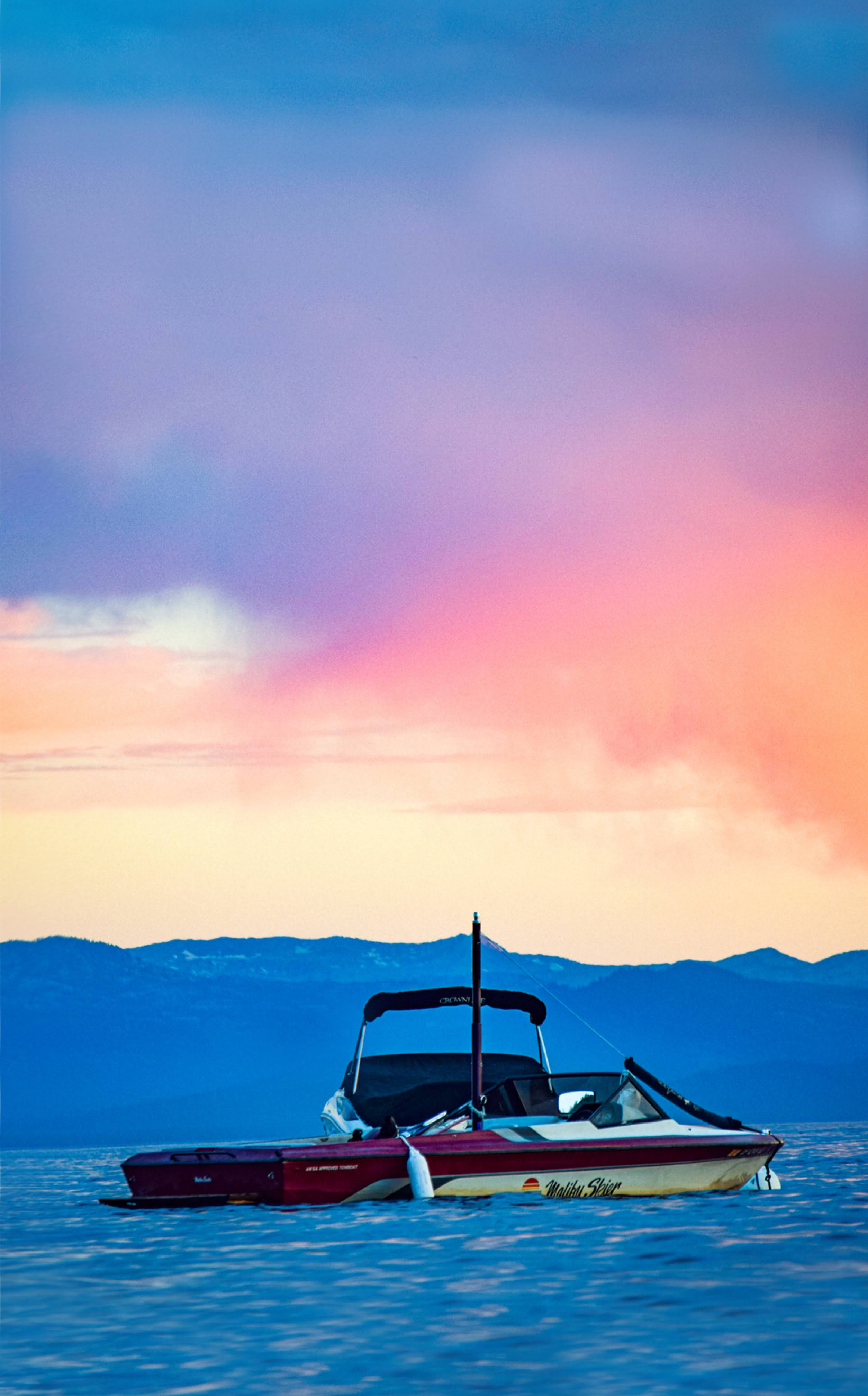 A boat moored on Lake Tahoe, silhouetted against a pastel pink and blue sunset sky